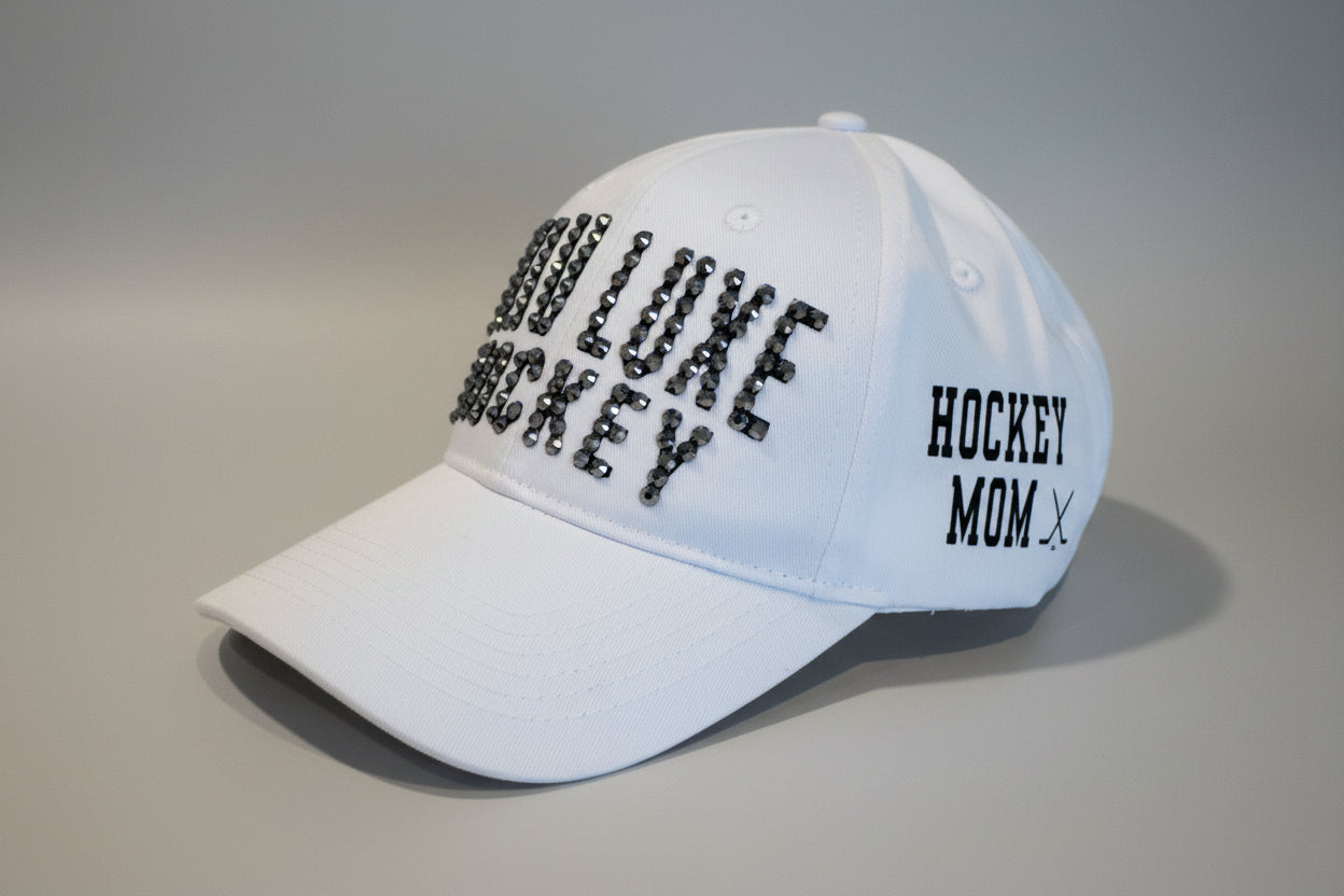 Glam Luxe Hockey Cap in white showing Hockey Mom crossed hockey sticks vinyl side detail — left side view