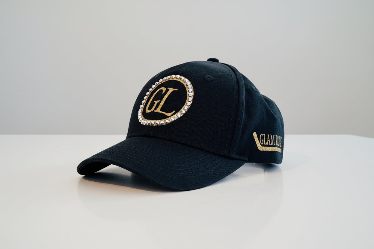 Glam Luxe Hockey™ Cap detail shot — gold glitter Glam Luxe text with hockey stick, rhinestone crystal rings, and GL monogram in black, pink, and white.

