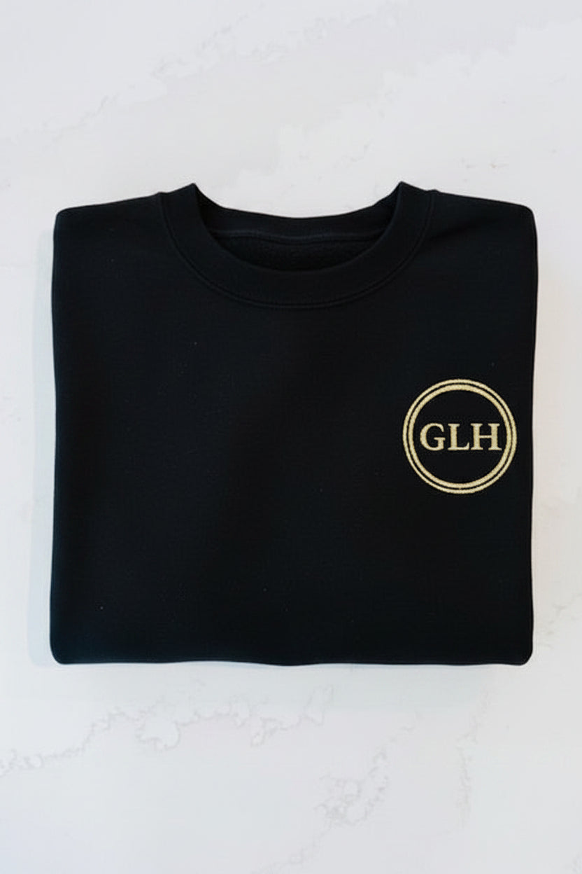 Glam Luxe Hockey black crewneck sweater with GLH gold glitter double-ring crest on left chest